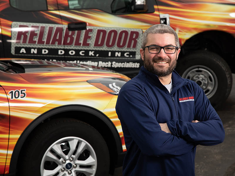Man standing in front of a Reliable Door and docks company vehicle